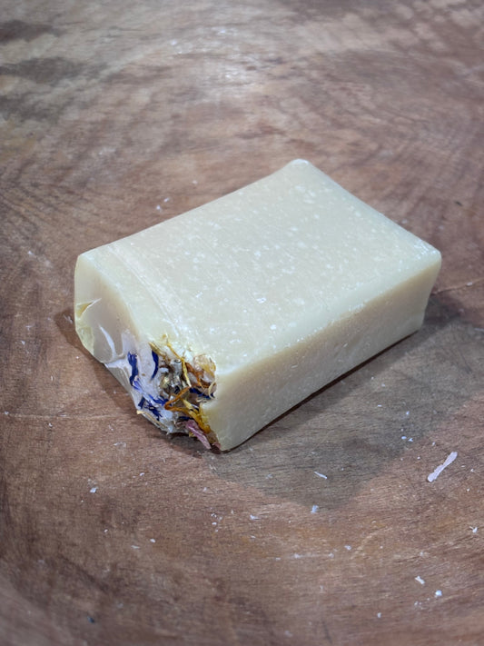 Blue Ridge Wildflower soap. Creamy pale yellow wildflower soap with dried botanical. Ingredients include saponified oils of olive, palm, coconut, and castor, fragrance oils, and dried botanicals.