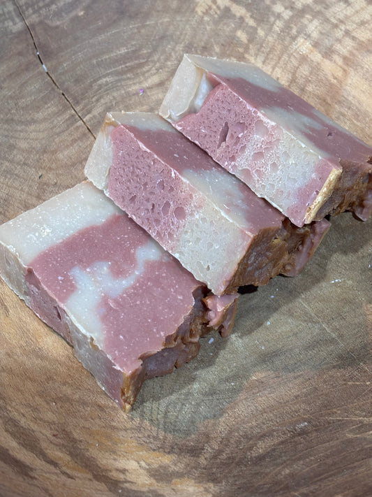 3 bars of pink and cream colored soap laying in a wooden bowl.

Ingredients include  saponified oils of olive, palm, coconut, castor, cocoa butter, avocado, fragrance oil and rose clay.