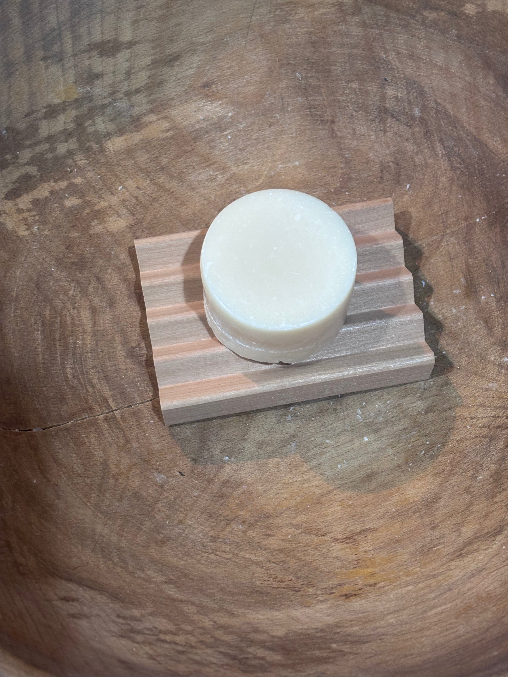 Bar of soap on a wooden soap dish against a wooden background
