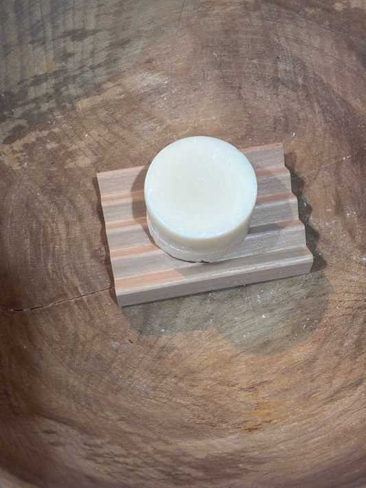 Bar of soap on a wooden soap dish against a wooden background