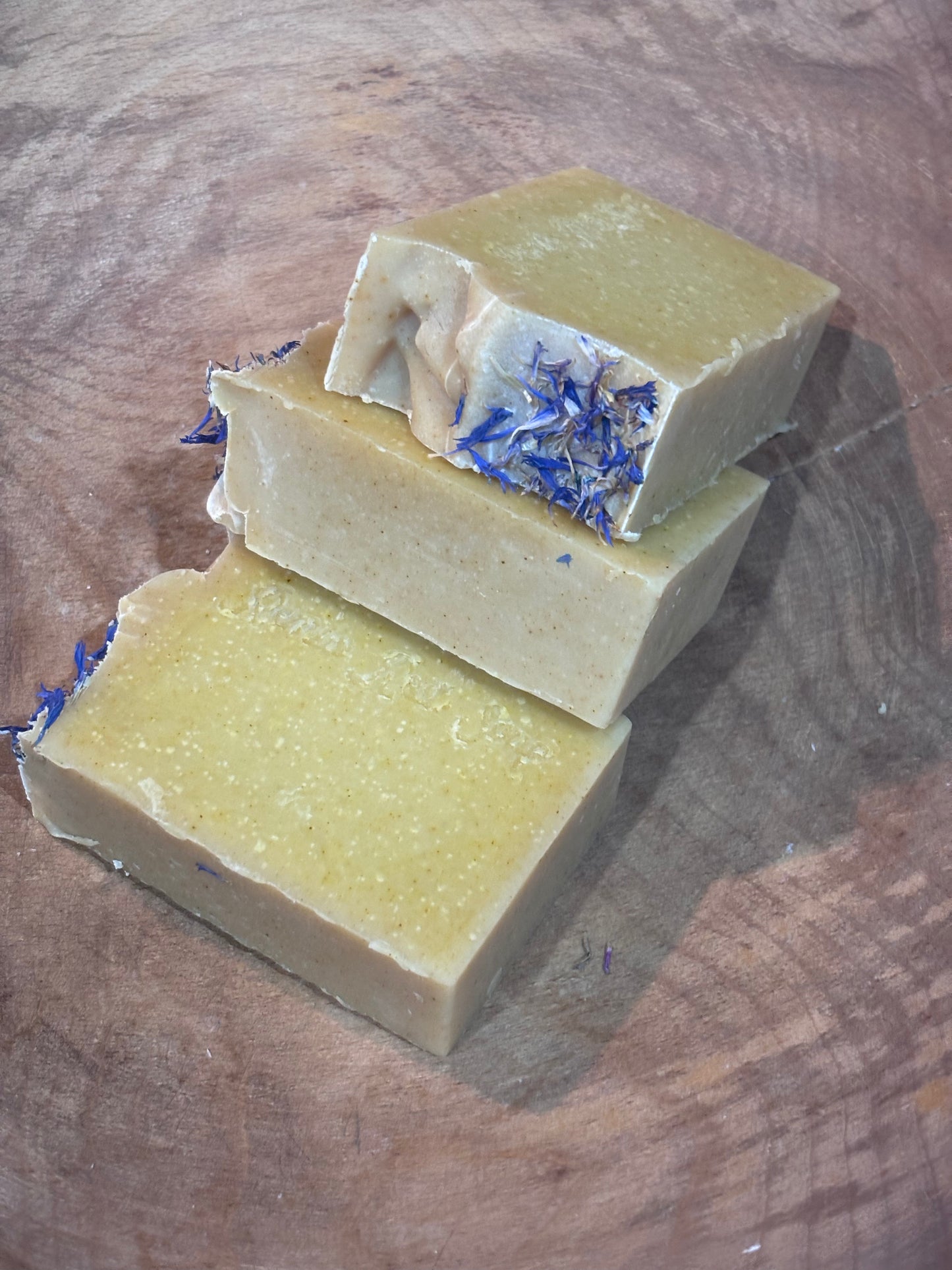 Three bars of dark yellow soap with blue cornflowers. Indian Summer Soap, a soft, warm, earthy floral scent with a touch of honey.