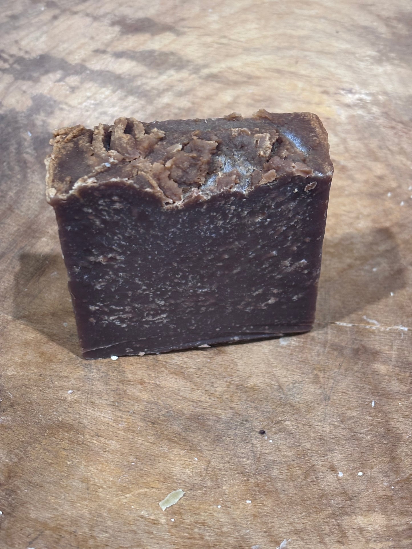 Dark brown spacing a wooden bowl. Pumpkin spice soap. Ingredients: saponified oils of olive, palm, coconut, castor, pumpkinseed and cocoa butter; distilled water; fragrance oil; sodium lactate (humectant)