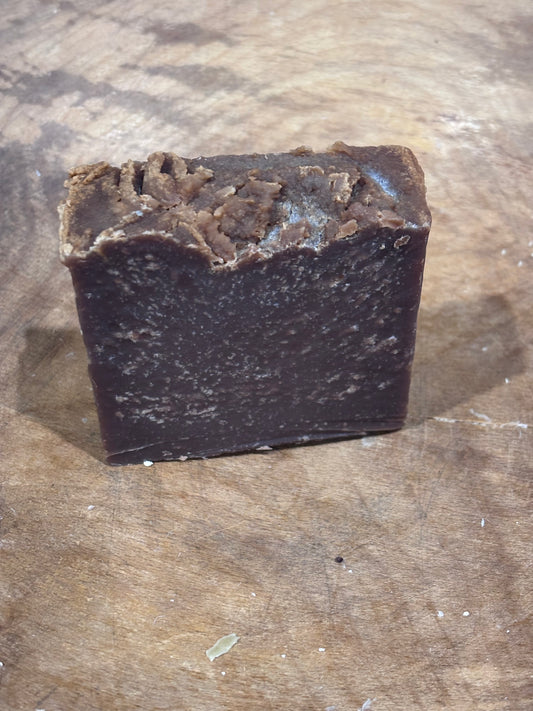 Dark brown spacing a wooden bowl. Pumpkin spice soap. Ingredients: saponified oils of olive, palm, coconut, castor, pumpkinseed and cocoa butter; distilled water; fragrance oil; sodium lactate (humectant)
