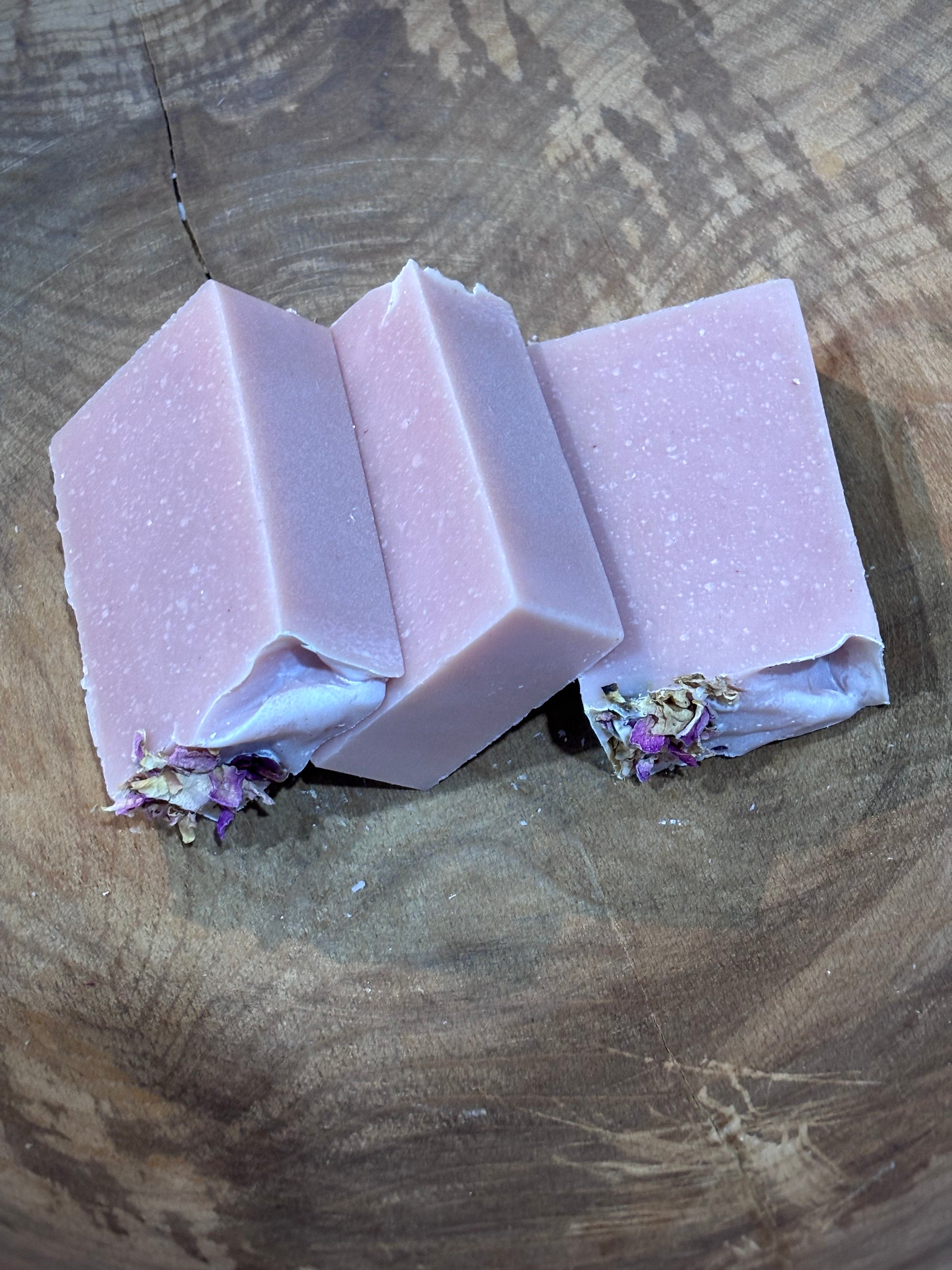 3 bars of peony scented soap. A creamy light pink soap bar topped with dried pink rose buds. Ingredients include saponified oils of olive, palm, coconut, castor, cocoa butter and avocado, fragrance oil, white kaolin clay and rose clay